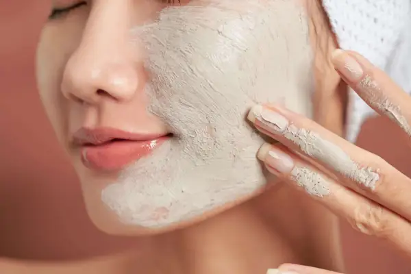 Une femme applique un masque d'argile sur son visage. Un tuto argile débutant pour une peau éclatante.