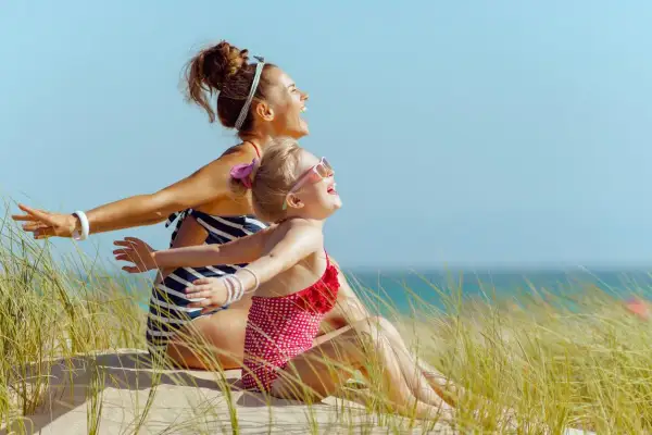 Mère et fille rient sur la plage, profitant du soleil. Un remède naturel contre la carence en vitamine D, même pour les plus jeunes.