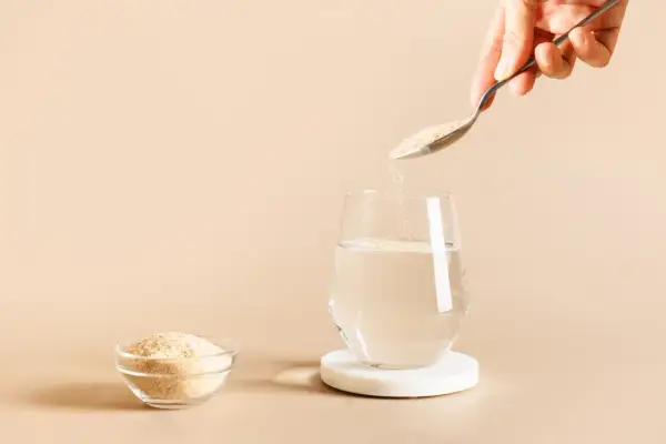 Une cuillère verse du psyllium dans un verre d'eau, une solution naturelle pour soulager la diarrhée.