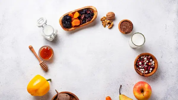 Un assortiment d'aliments bons pour l'estomac et les intestins : fruits secs, noix, graines de lin, haricots, lait, miel, poivron, betterave, pomme et poire.