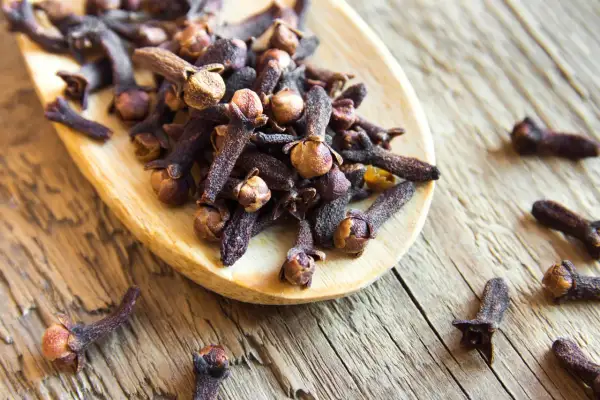 Girofles sur une cuillère en bois, évoquant leur potentiel dans la gestion de l'hypertension.
