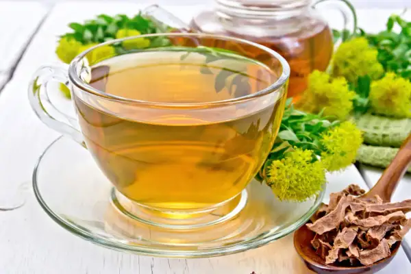 Une tasse de thé ambré, des fleurs de rhodiola et des racines séchées. Attention, la rhodiola peut présenter un danger si mal utilisée.