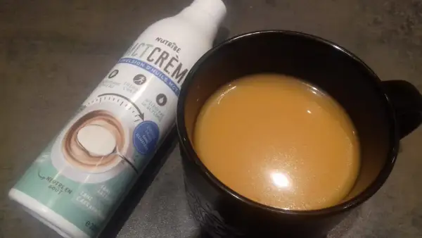 Bouteille d'émulsion d'huile MCT et une tasse de boisson. Attention à l'huile MCT, danger potentiel si mal utilisée.