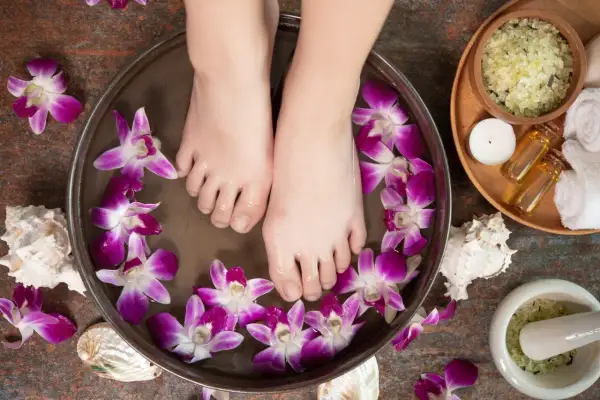 Pieds dans un bain de fleurs d'orchidée et de sel d'Epsom pour un moment de détente.